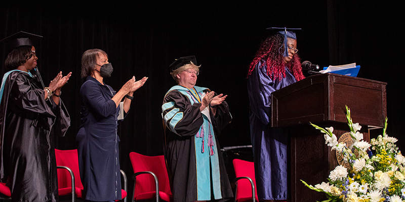 Graduate speaking at podium.